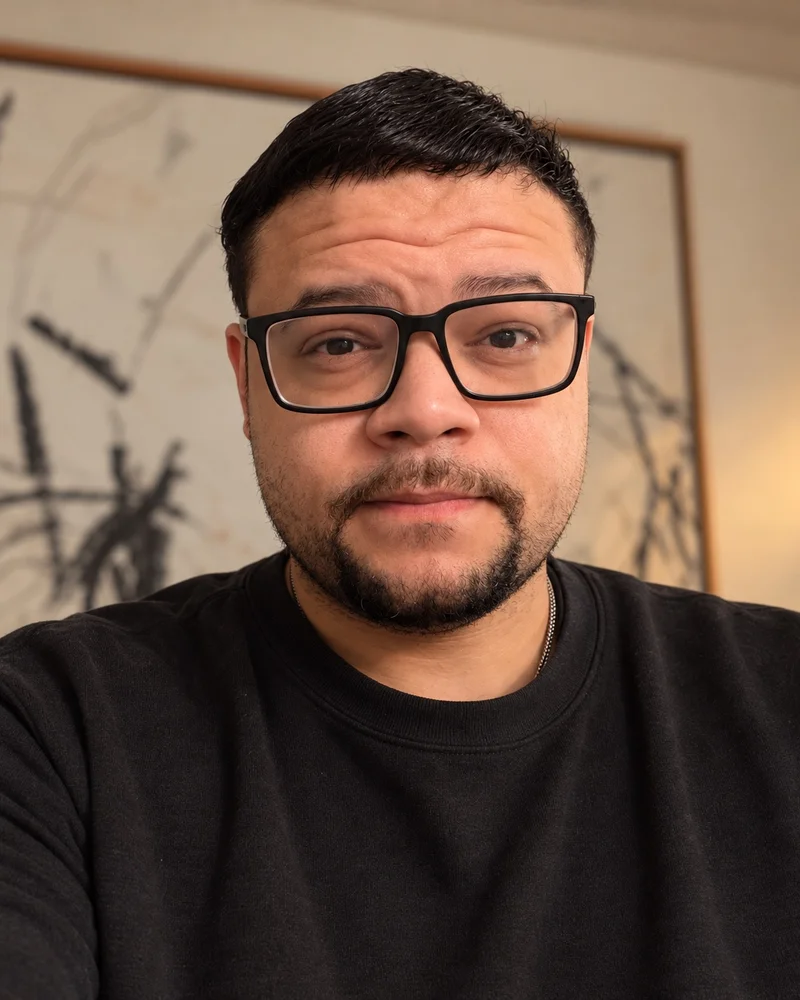 Jordan Sandrini-Cooke wearing black glasses and a dark crewneck.